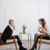 Executive Coaching Session: Führungskraft im professionellen Hypnose-Beratungsgespräch in elegantem Büroambiente
