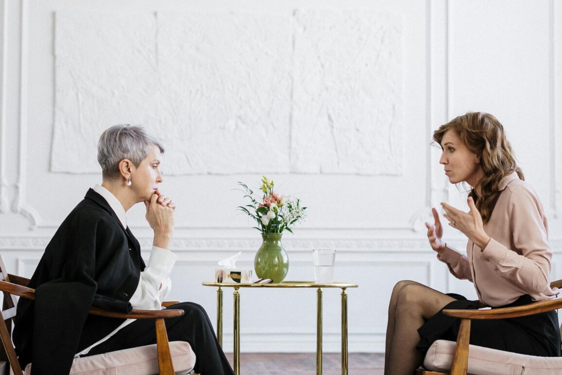 Executive Coaching Session: Führungskraft im professionellen Hypnose-Beratungsgespräch in elegantem Büroambiente
