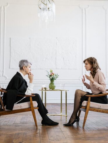 Executive Coaching Session: Führungskraft im professionellen Hypnose-Beratungsgespräch in elegantem Büroambiente