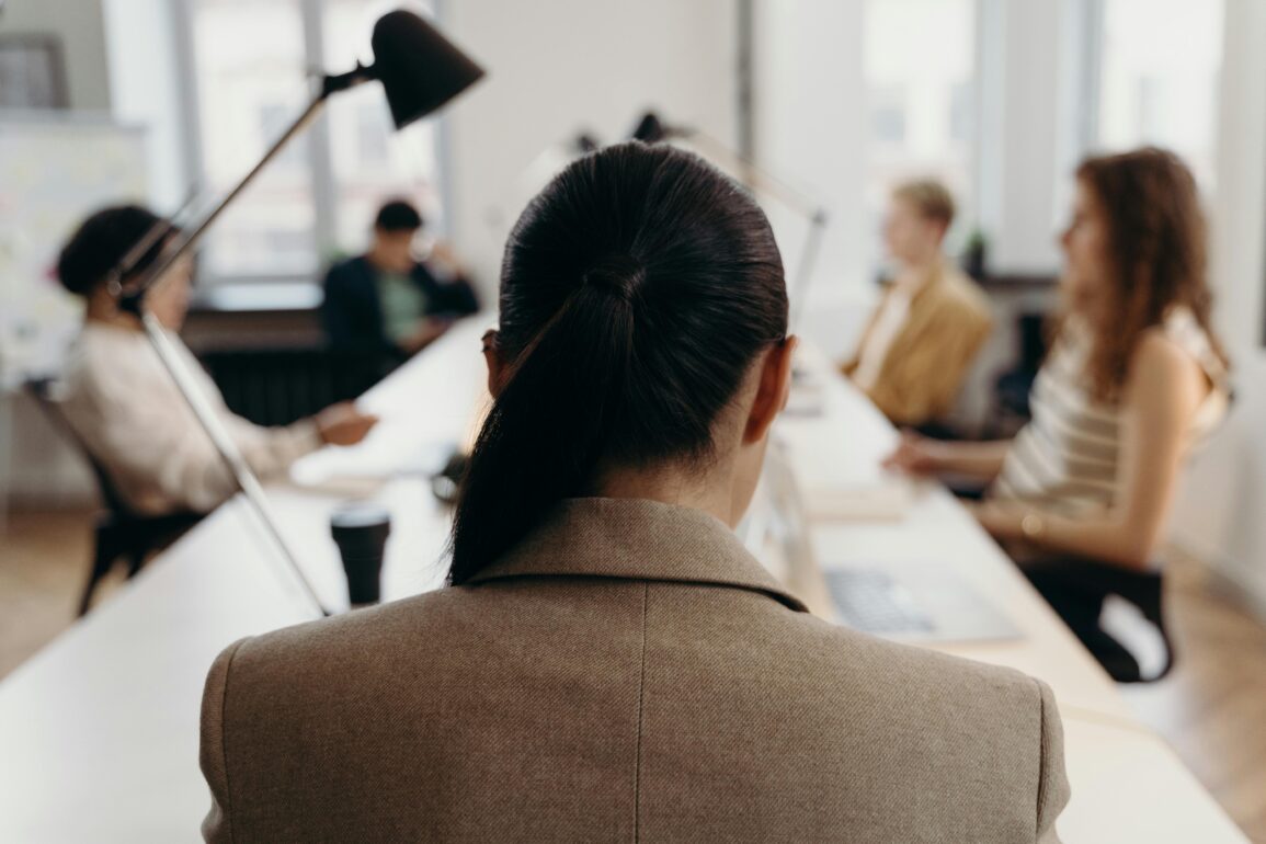 Führungskraft in beigem Blazer sitzt in modernem Büro während Managementmeeting - Unconscious Bias in Führungsentscheidungen vermeiden