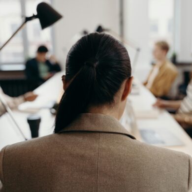 Führungskraft in beigem Blazer sitzt in modernem Büro während Managementmeeting - Unconscious Bias in Führungsentscheidungen vermeiden