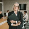 "Professionelle Geschäftsfrau mit Ordner in Konferenzraum - High Level Networking zwischen Führungskräften"