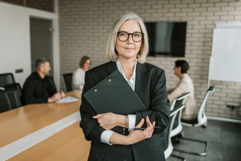 "Professionelle Geschäftsfrau mit Ordner in Konferenzraum - High Level Networking zwischen Führungskräften"